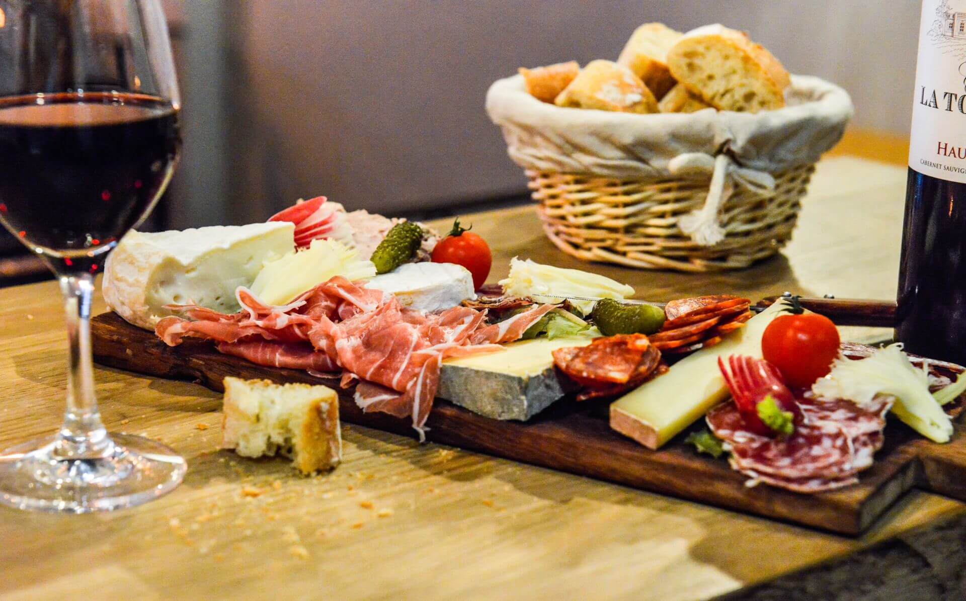 Une planche de charcut' et de frometons accompagné de d'une baguette tradition et d'un bon verre de vin